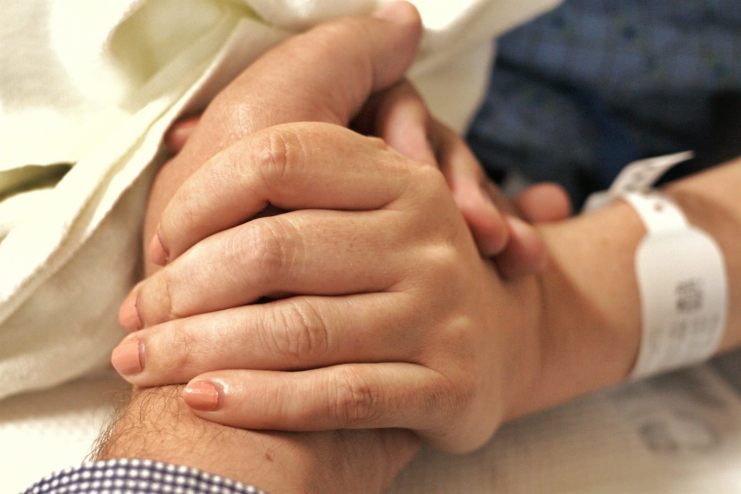 Two hands, one older and one younger, held together gently