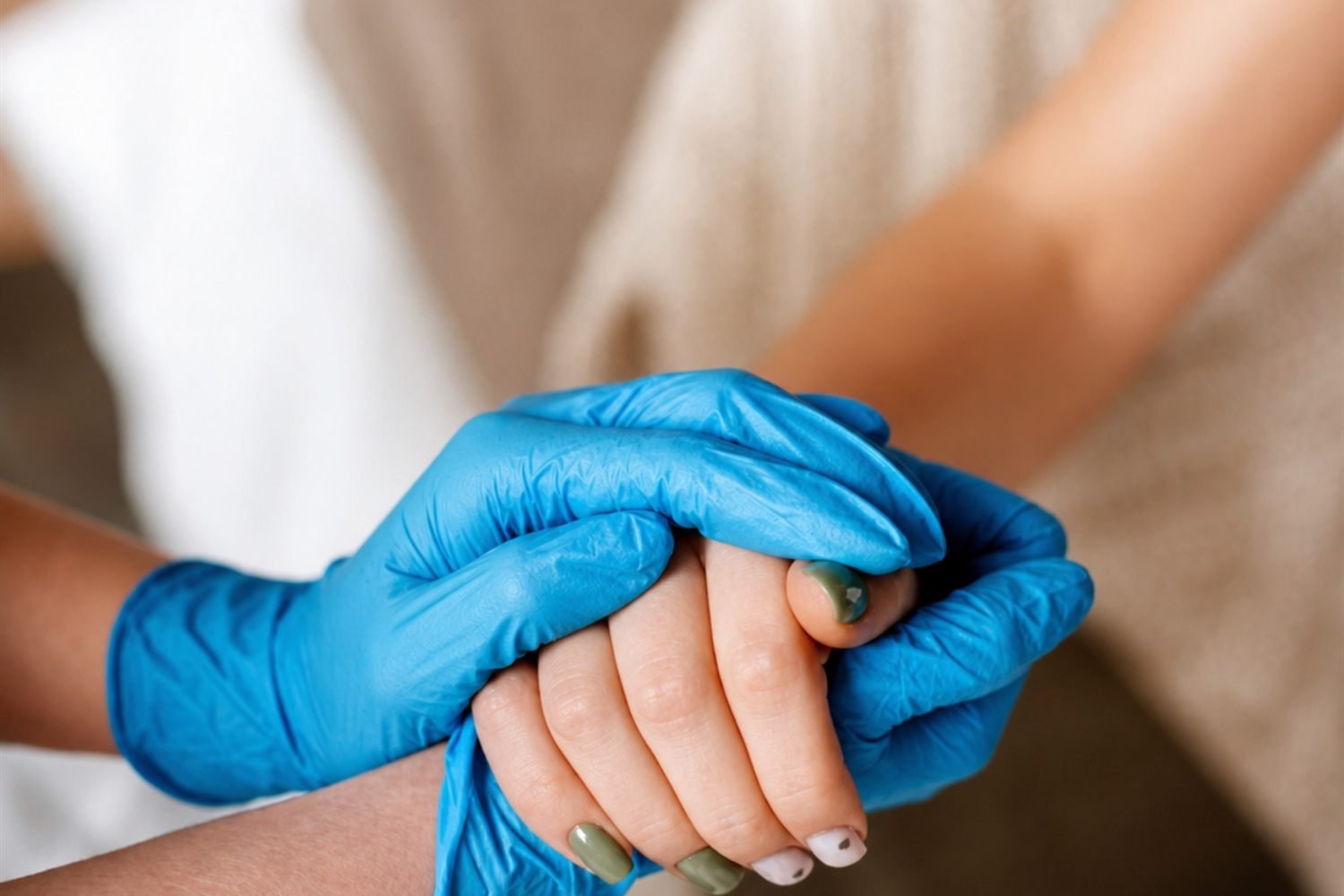 A care provider sitting beside a patient's bed, hands clasped together